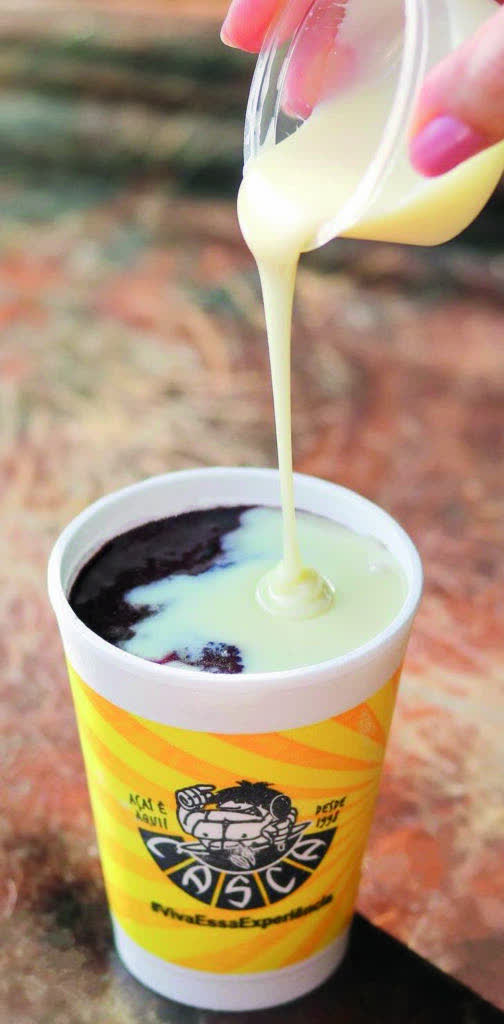 Leite condensado sendo servido sobre açaí em copo oficial do Casca Açaí.
