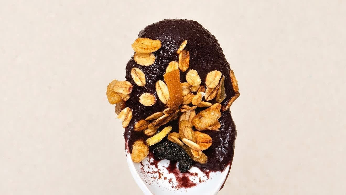 Colher com açaí cremoso coberto de granola.